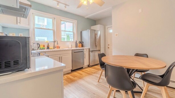Une cuisine de taille réduite avec un coin repas, un ventilateur de plafond et un réfrigérateur.