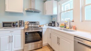 Une cuisine moderne avec des armoires blanches, une cuisinière en acier inoxydable, un four à micro-ondes et un lave-vaisselle.