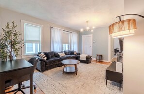 A living room with a sofa, a coffee table, a lamp, and a plant.