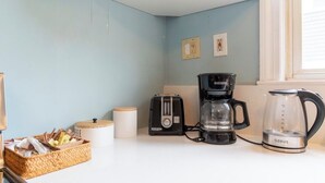 Une cuisine équipée d’une machine à café, d’une verseuse en verre, d’un grille-pain et d’un panier en osier contenant divers objets.