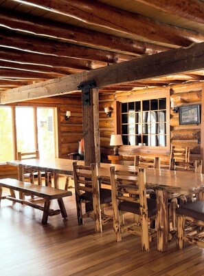 A rustic wooden interior with exposed beams, a large wooden dining table, and benches. - Family ready, 9-bedroom, 7.5-bathroom cabin with AC in charming Birchwood (Birchwood)