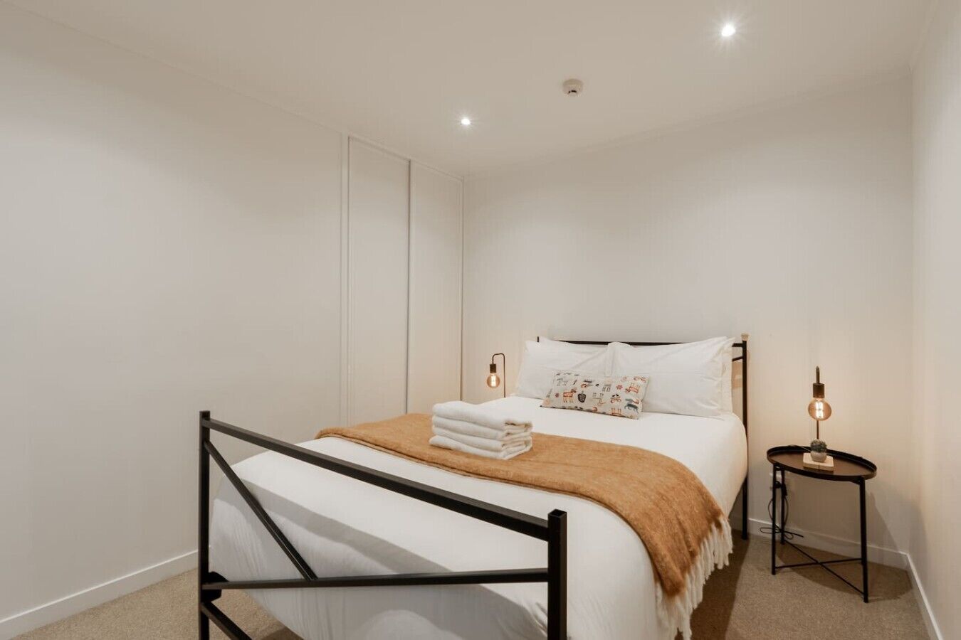 A bedroom with a bed, bedside tables, and a ceiling light.