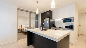 Een moderne keuken met een centraal eiland, roestvrijstalen apparatuur en hanglampen.