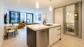 Een moderne keuken met een centraal eiland, een zithoek met een bank en stoelen, en een grote schuifpui naar een balkon.