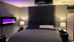 A modern hotel room with a bed, bedside lamps, a wall-mounted TV, and a ceiling light fixture.