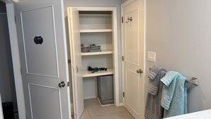 A bathroom with a white sink, a towel rack with towels, and a door leading to a closet with shelves.