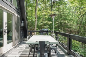 Eine Terrasse im Freien mit Tisch, Stühlen, einem Grill und einer Lampe.