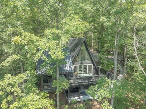 A cabin surrounded by dense forest. - Luxe A-frame Hideaway, mountain views, hot tub, outdoor patio w/fireplace (Blairsville)
