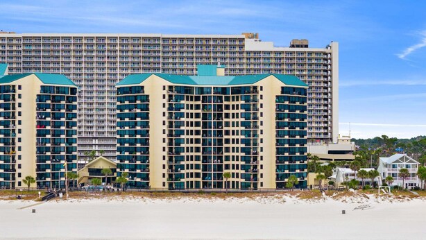 Un hôtel situé en bord de mer, composé de plusieurs immeubles de grande hauteur, avec une plage de sable fin et une eau turquoise.