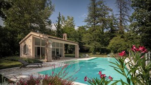 A pool with a clear blue water, surrounded by a garden with pink flowers, and a building with a tiled roof. - Cosy apartment on a tranquil estate with shared pool & mountain views (Marche)