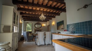A kitchen with a wooden ceiling, a chandelier, a dining area with striped chairs, and a tiled backsplash. - Cosy apartment on a tranquil estate with shared pool & mountain views (Marche)