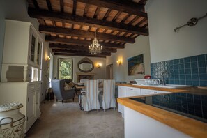A kitchen with a wooden ceiling, a chandelier, a dining area with striped chairs, and a tiled backsplash. - Cosy apartment on a tranquil estate with shared pool & mountain views (Marche)