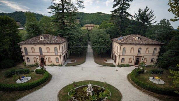 A symmetrical building with a central garden and a pathway leading to it. - Cosy apartment on a tranquil estate with shared pool & mountain views (Marche)