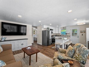 A modern living room with a flat-screen TV, a wooden coffee table, and a patterned sofa. - Robyn's Nest - 2 Bedroom 2 Bathroom Beach Home (Englewood)