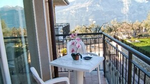 Un balcone con tavolo e sedie, un vaso con fiori e vista sulle montagne.