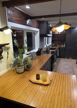 A modern kitchen with wooden countertops, a built-in stove, and a window with a view.
