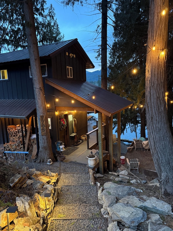 A rustic cabin with a covered porch, wooden deck, and a view of the water.