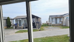 A view through a window of a residential area with houses, a grassy lawn, and a paved road. - Sun Retreats Sherkston Shores (Port Colborne)