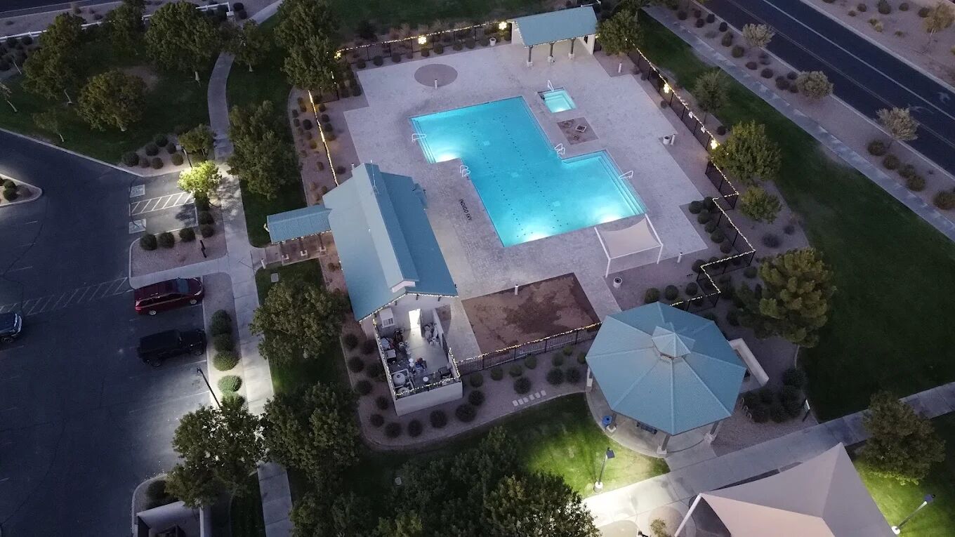 An aerial view of a property with a swimming pool, a covered patio, and a small gazebo.