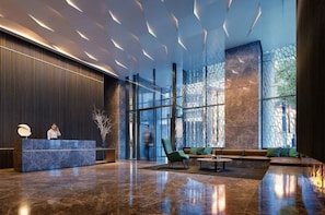 A modern lobby with a reception desk, seating area, and large windows. - Royal Executive Living  Sky Corporate Residence (Melbourne)