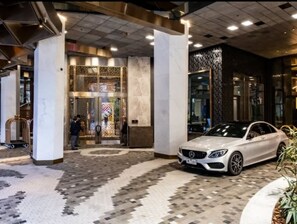 A hotel entrance with a white car parked outside, a patterned floor, and a large decorative gate. - Level 69 Bay Views & Japanese Soaking Tub (Melbourne)
