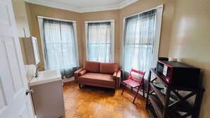 A living room with a sofa, a chair, a microwave, and a door.