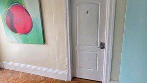 A white door with the number 3, a green abstract painting, and a wooden floor.