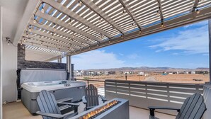 A balcony with a hot tub, seating, and a fire feature. - Sun-Filled Coastal Home | Lagoon Access| Hot Tub| Sleeps 12 (St. George)