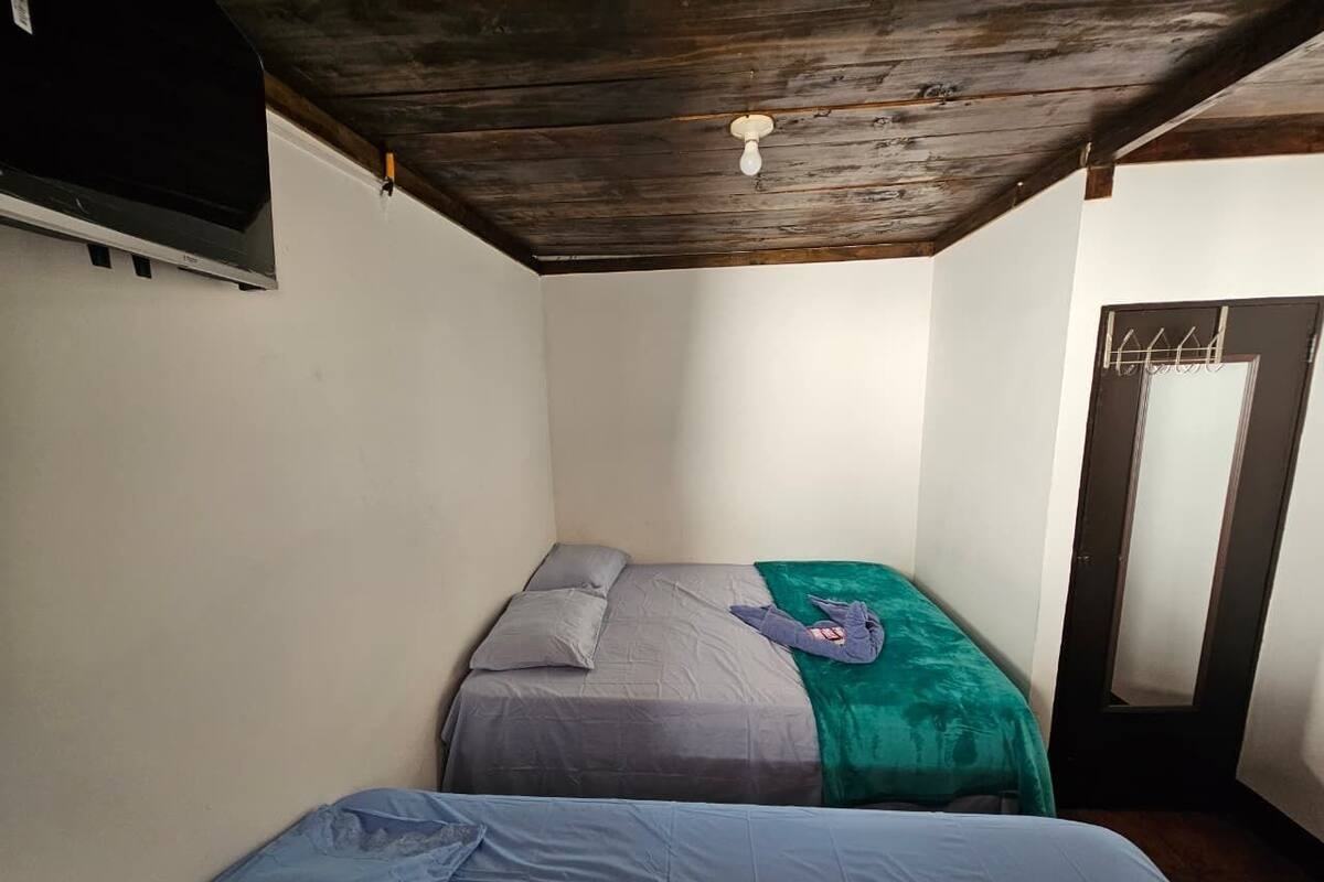 Ein kleines Zimmer mit zwei Betten, einer Holzbalkendecke und einer Tür mit Spiegel.