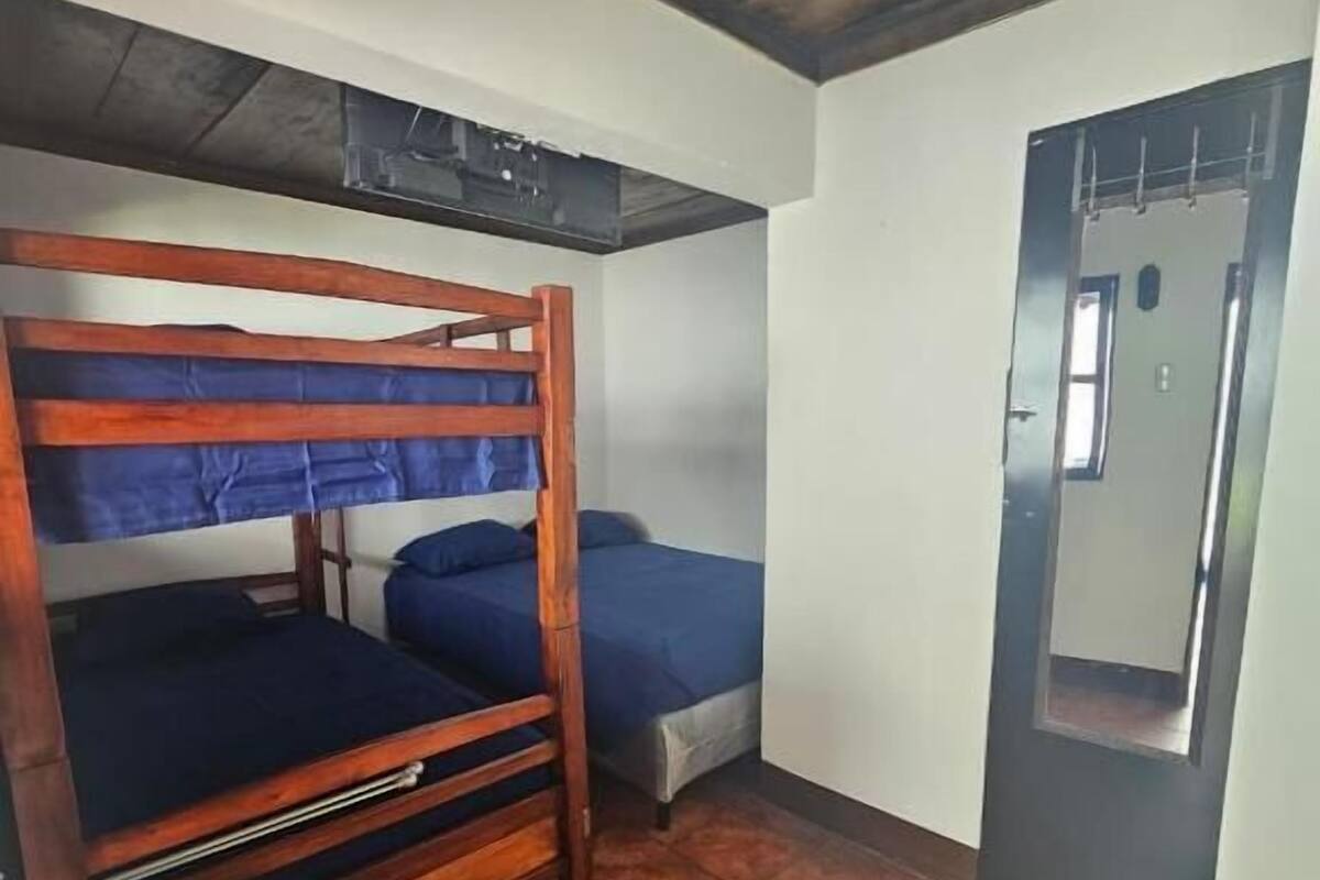 Ein Zimmer mit einem Etagenbett, einem Einzelbett, einem Fliesenboden und einer Tür mit Spiegel.