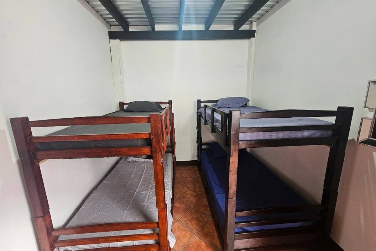 Ein Zimmer mit zwei Holzbettställen, einem Fliesenboden und einem Metalldach.