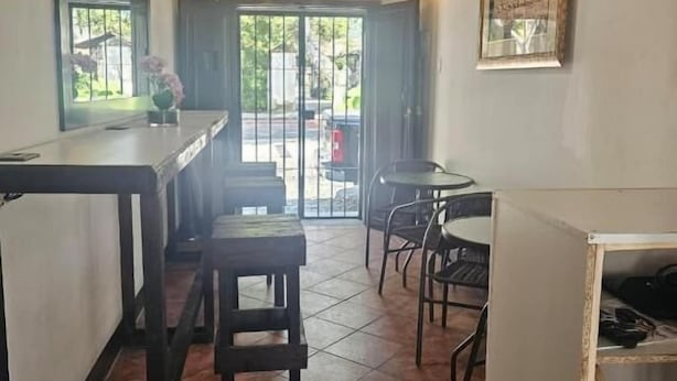 A restaurant with a bar area, seating, and a view through the glass doors. - Hotel y restaurante pura vida (Antigua Guatemala)