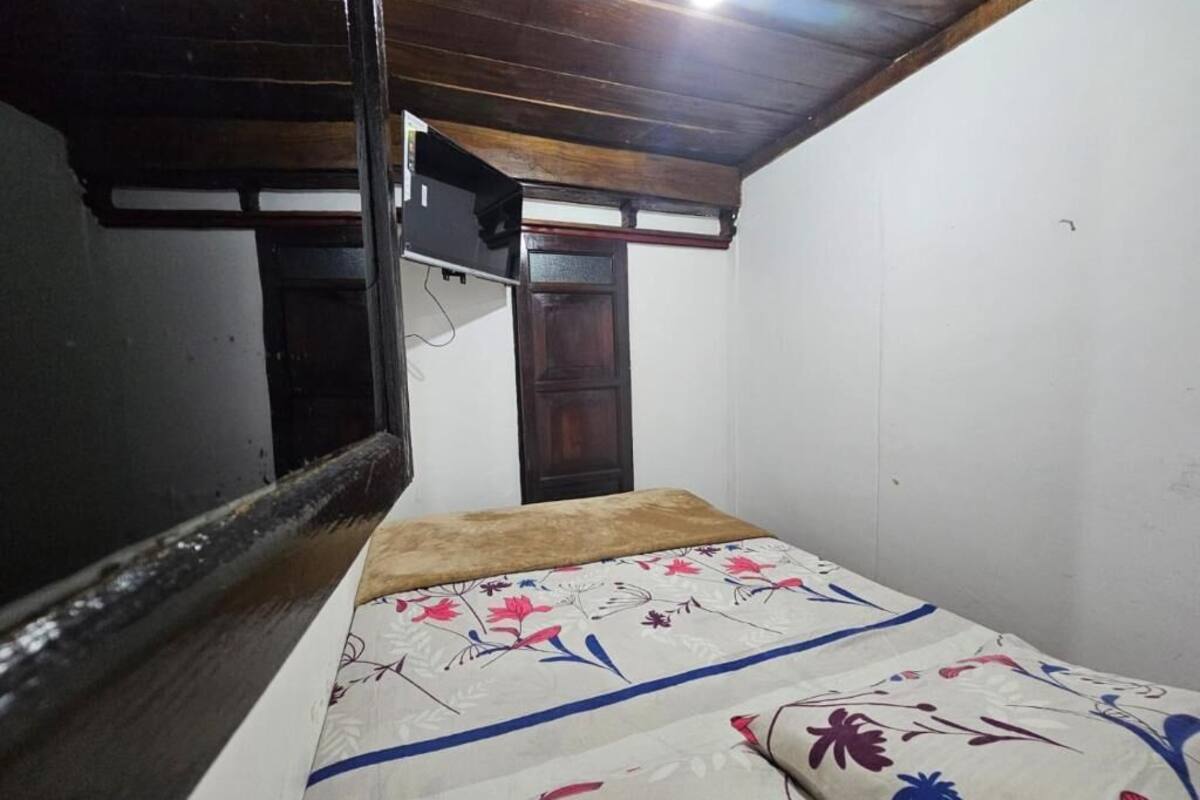 Ein Zimmer mit einem Bett, einer Holzbalkendecke, einer weißen Wand und einer Tür.