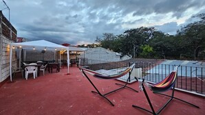 A patio with a red floor, two hammocks, a table with chairs, and a white tent. - Hotel y restaurante pura vida (Antigua Guatemala)