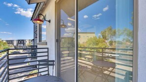 Un balcon avec une table et des chaises, une balustrade et une vue sur la rue et les immeubles.