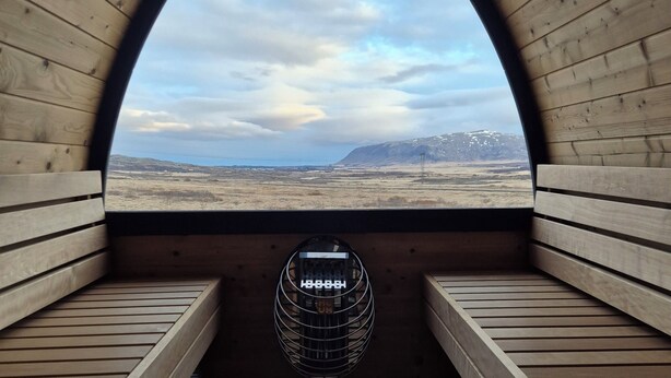 Una sauna con un banco de madera, una ventana circular y un calentador de metal.