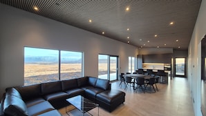 Una sala de estar moderna con un sofá seccional, una mesa de centro de vidrio y grandes ventanales que ofrecen vistas a un paisaje desértico.