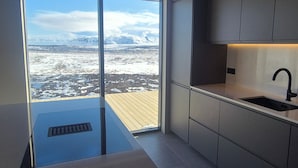 Una cocina moderna con un ventanal grande, un fregadero y vistas a un paisaje nevado.