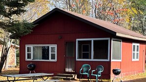 A red cabin with a picnic table and two chairs in front. - Beavers Resort - Cabin 1 (Mercer)