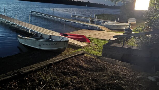 A calm lake with docked boats, a wooden pier, and a grassy area. - Beavers Resort - Cabin 1 (Mercer)