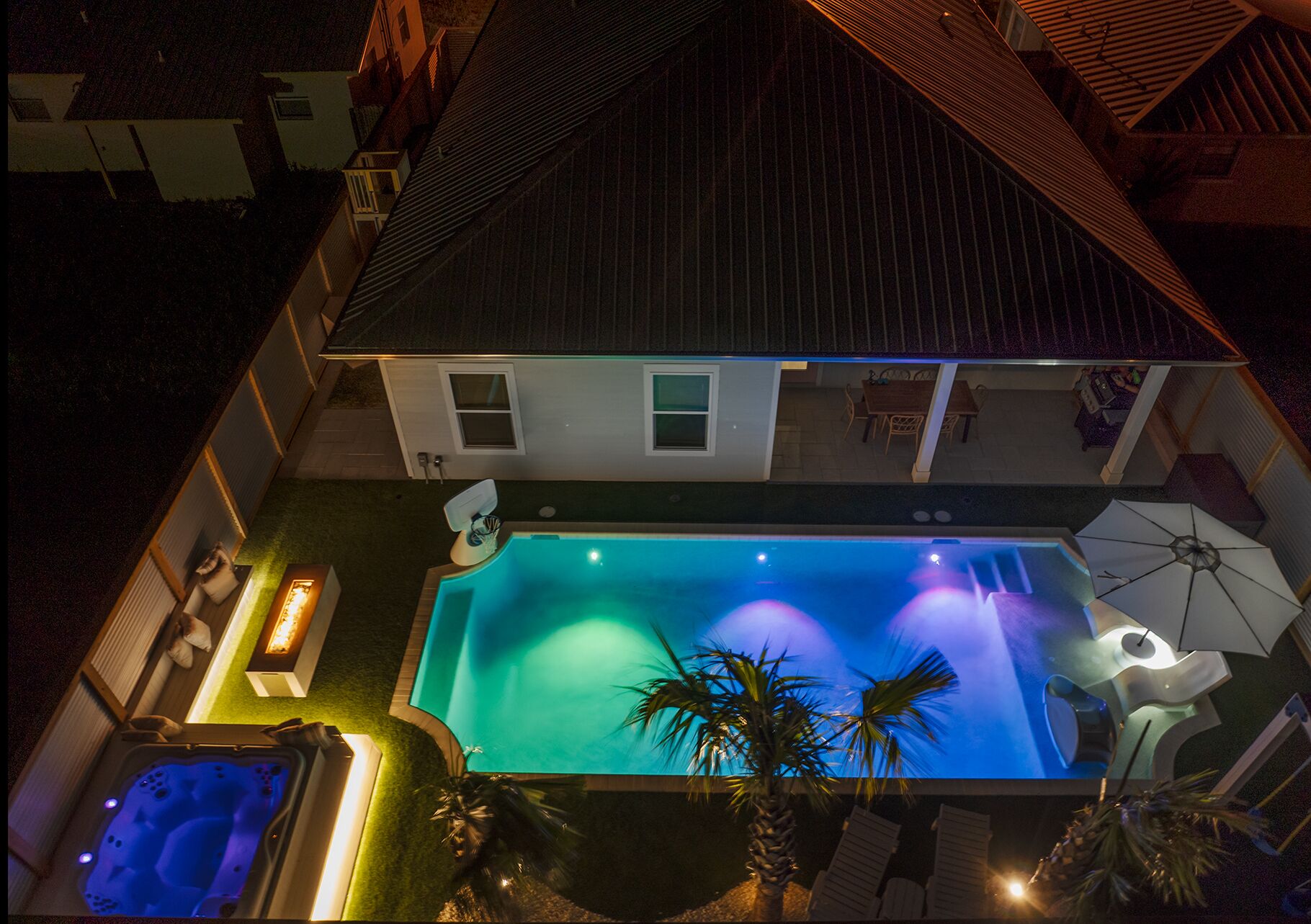 Una casa con piscina, vasca idromassaggio e patio attrezzato con sedie e ombrelloni.