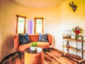 Ett mysigt vardagsrum med en soffa, ett soffbord, ett dekorativt hjorthuvud och en bokhylla.
