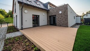 Une maison moderne dotée d’une terrasse, d’un garage et d’un mur en briques.