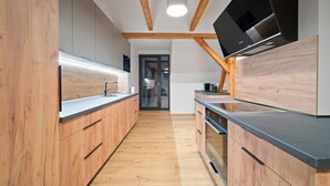 Une cuisine moderne avec des meubles en bois, un four encastré et un grand téléviseur à écran plat.