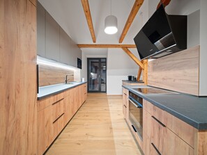 Una cocina moderna con armarios de madera, horno empotrado y un televisor de pantalla plana grande.