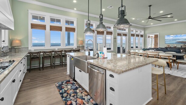 A spacious kitchen with a large island, pendant lighting, and a view to the outside. - Beachfront Retreat Sleeps 30 with Swim Spa, Fire Pit and Putt-Putt (Bolivar Peninsula)