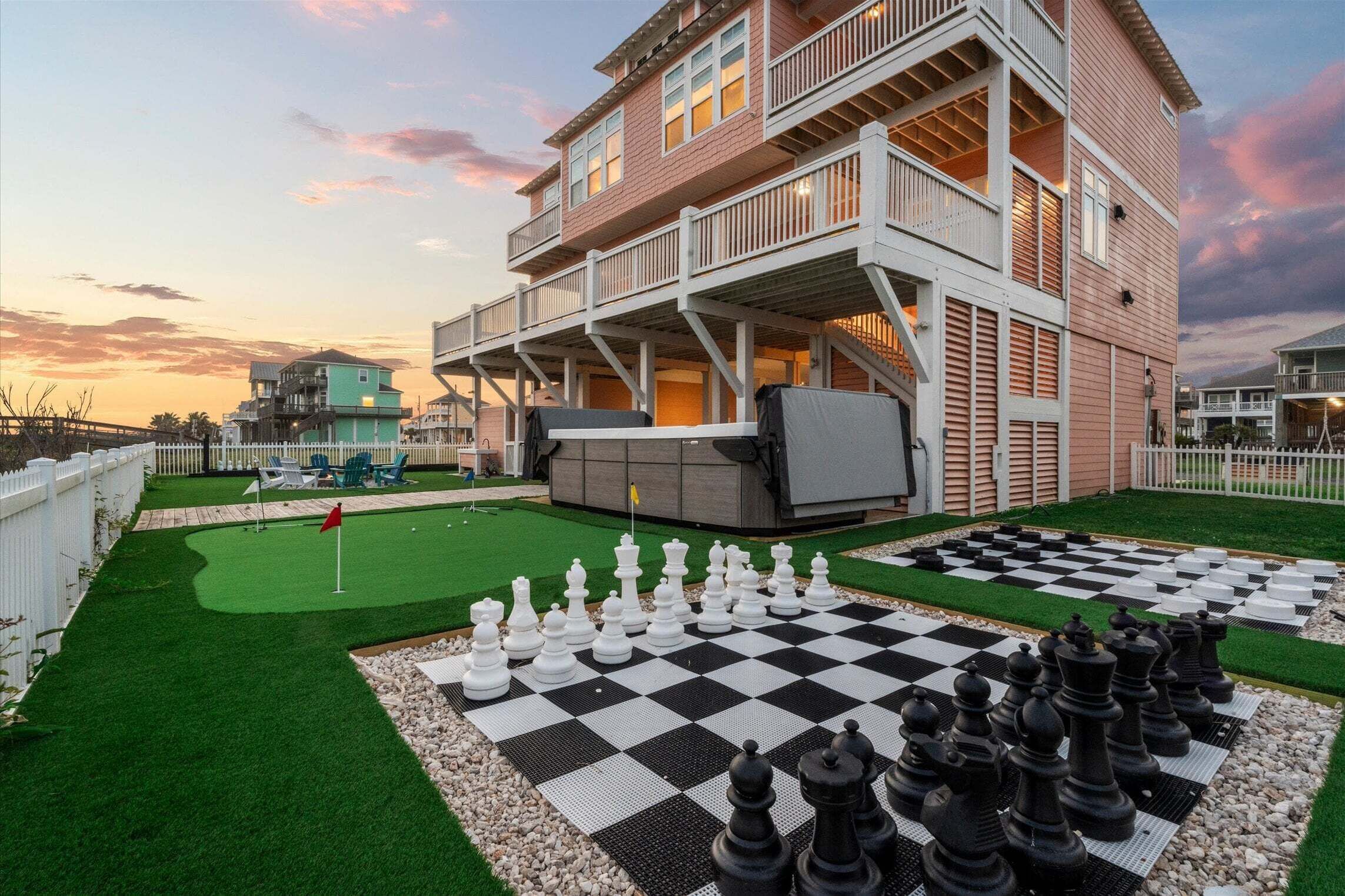 A multi-story building with a deck, a checkered outdoor chessboard, and a putting green.