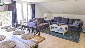 Un saló modern amb zona de menjador, sofà i taula de centre.
