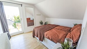 Un dormitori amb un llit, una finestra, un mirall i una planta en test.