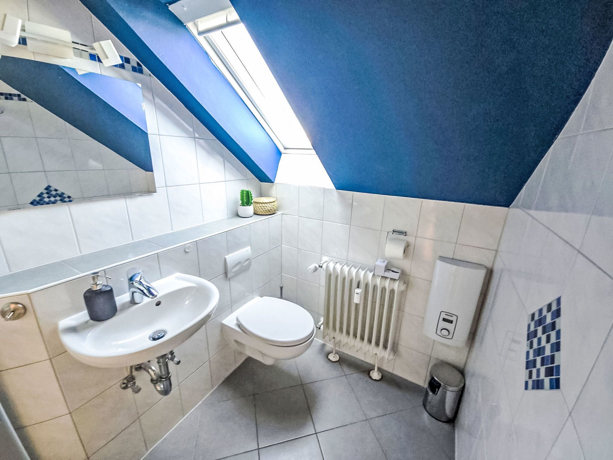 A modern bathroom with a sink, toilet, and radiator.